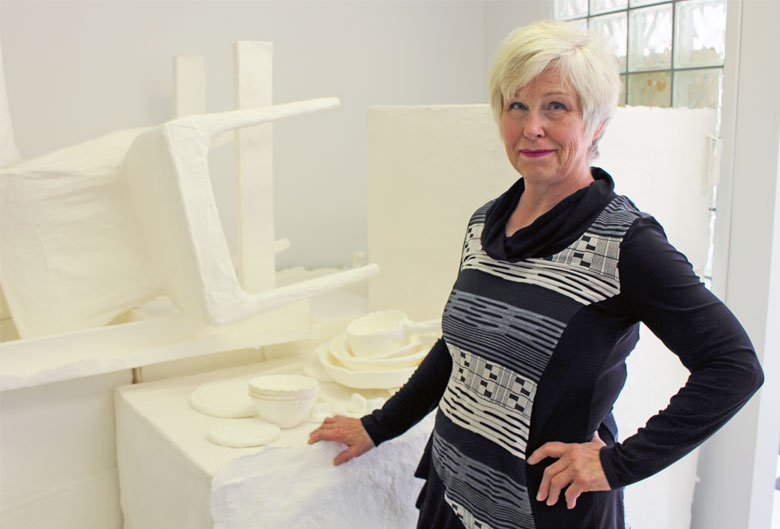 Woman standing by objects cast in paper