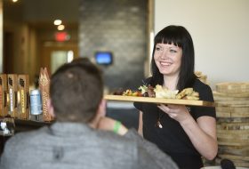 A server passing food to customers at CrossRoads