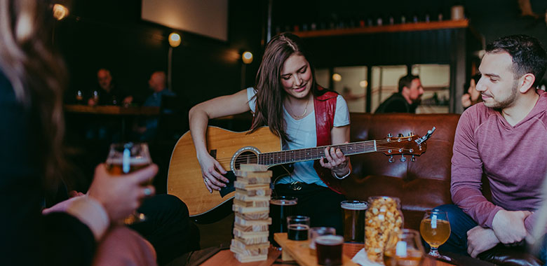 People in brewery having beer and playing guitar