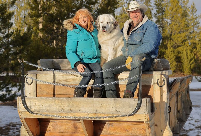 Woman, dog, and man, sitting on sleigh.